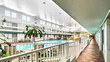 An indoor swimming pool with a brick floor, white railings, and multiple levels with balconies.