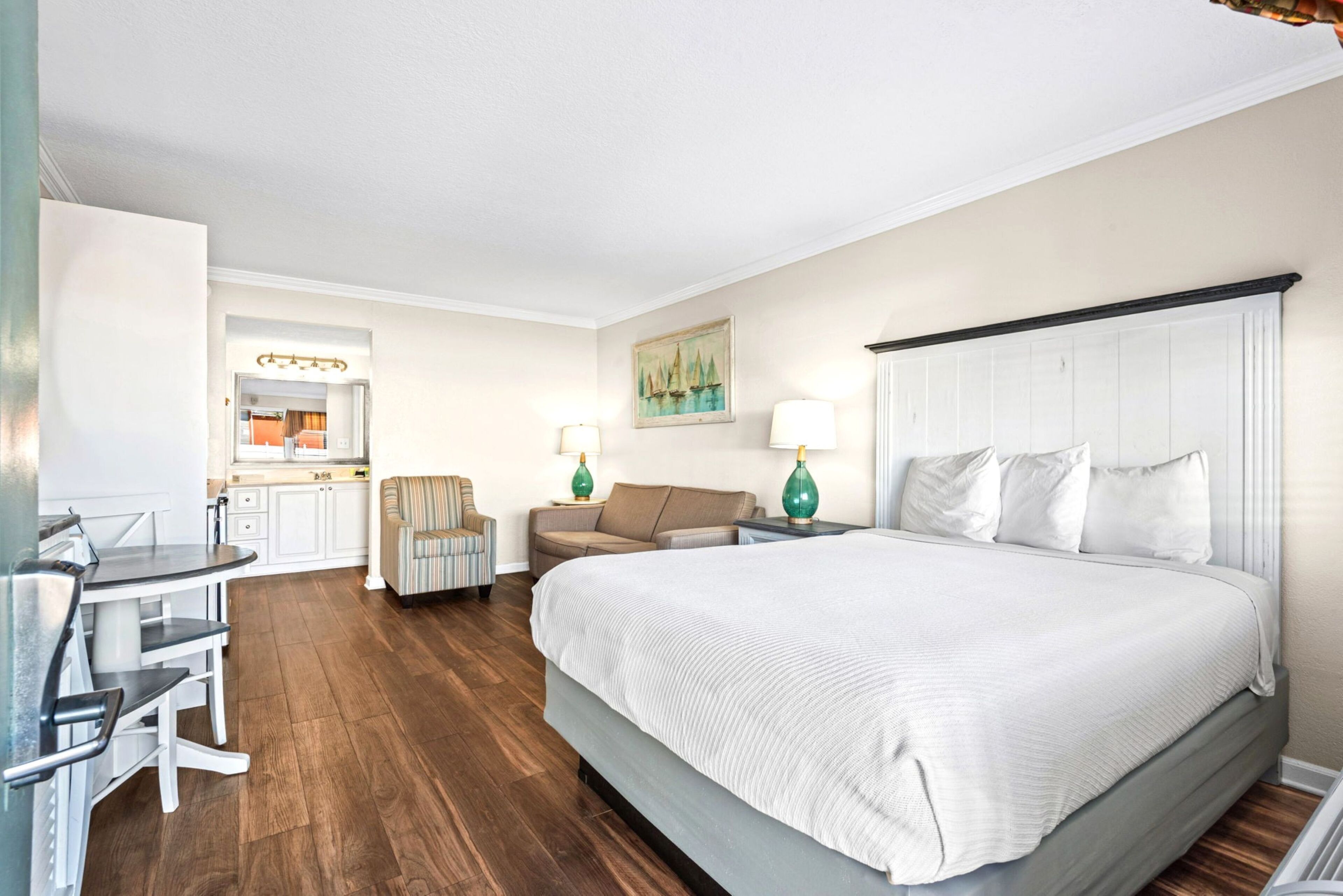 A hotel room with a bed, a desk, a chair, a sofa, and a small table.