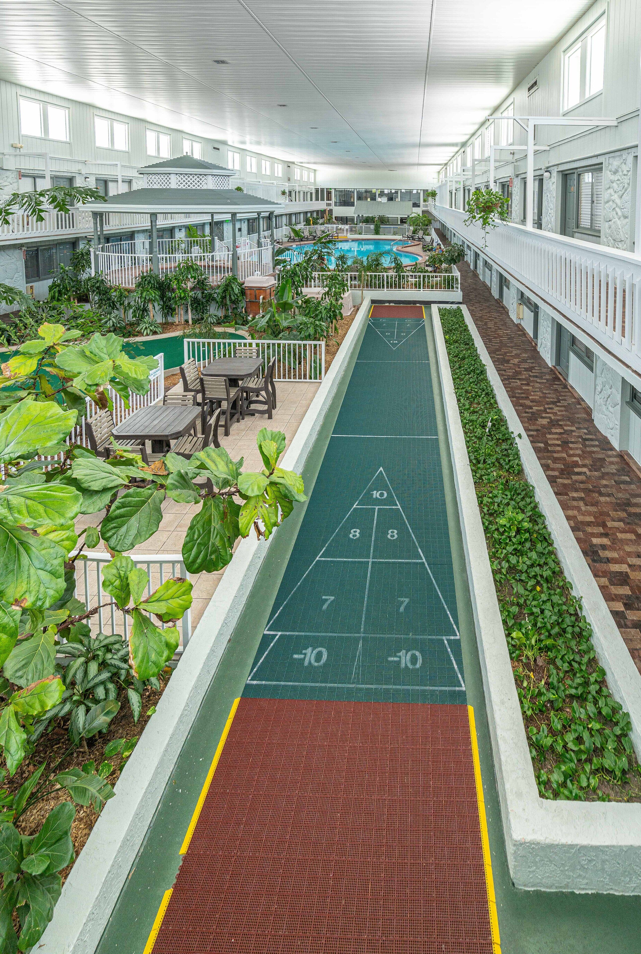 Une longue piste de jeu de palet intérieur, avec une piscine en arrière-plan.