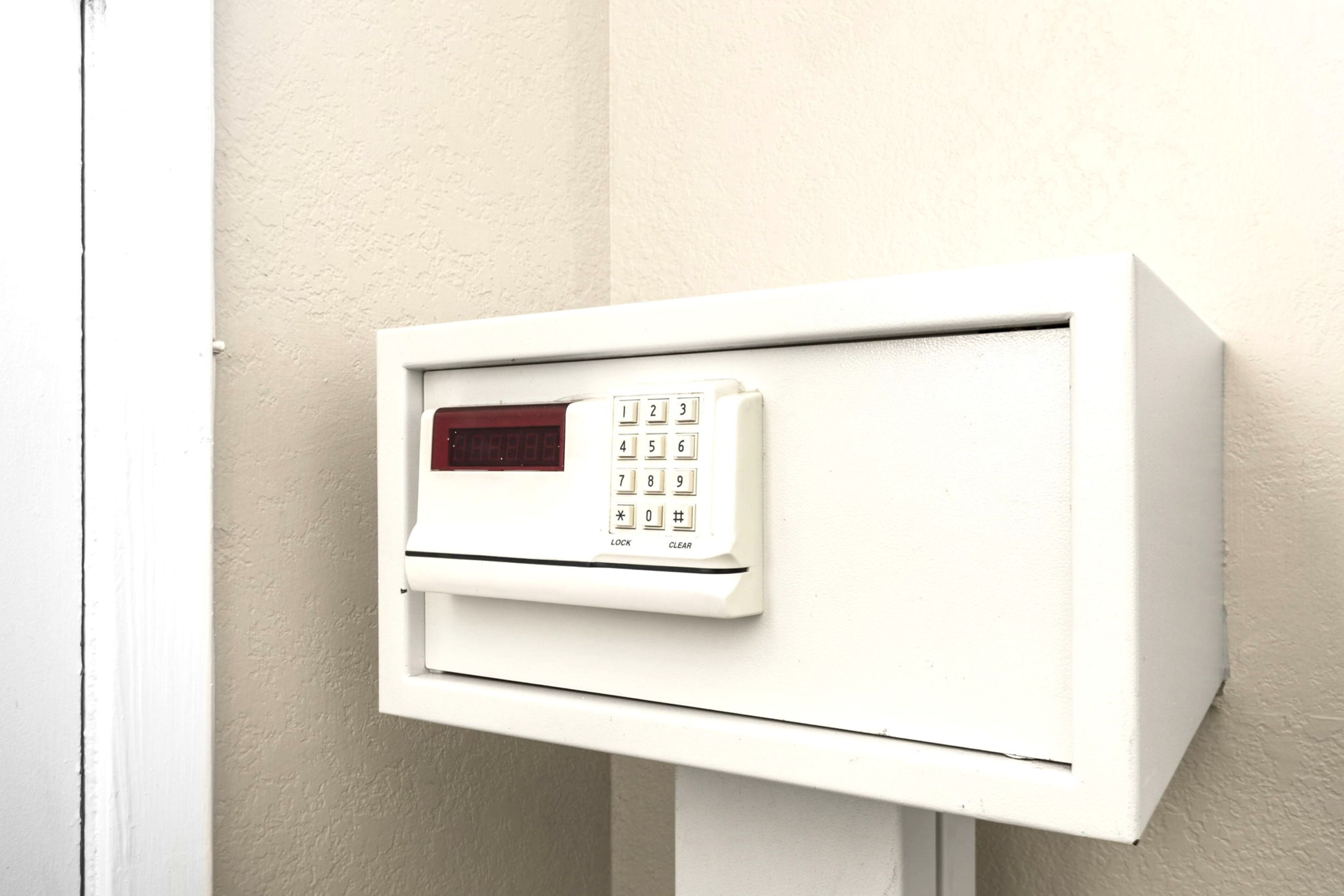 A white intercom box with a keypad, mounted on a wall.