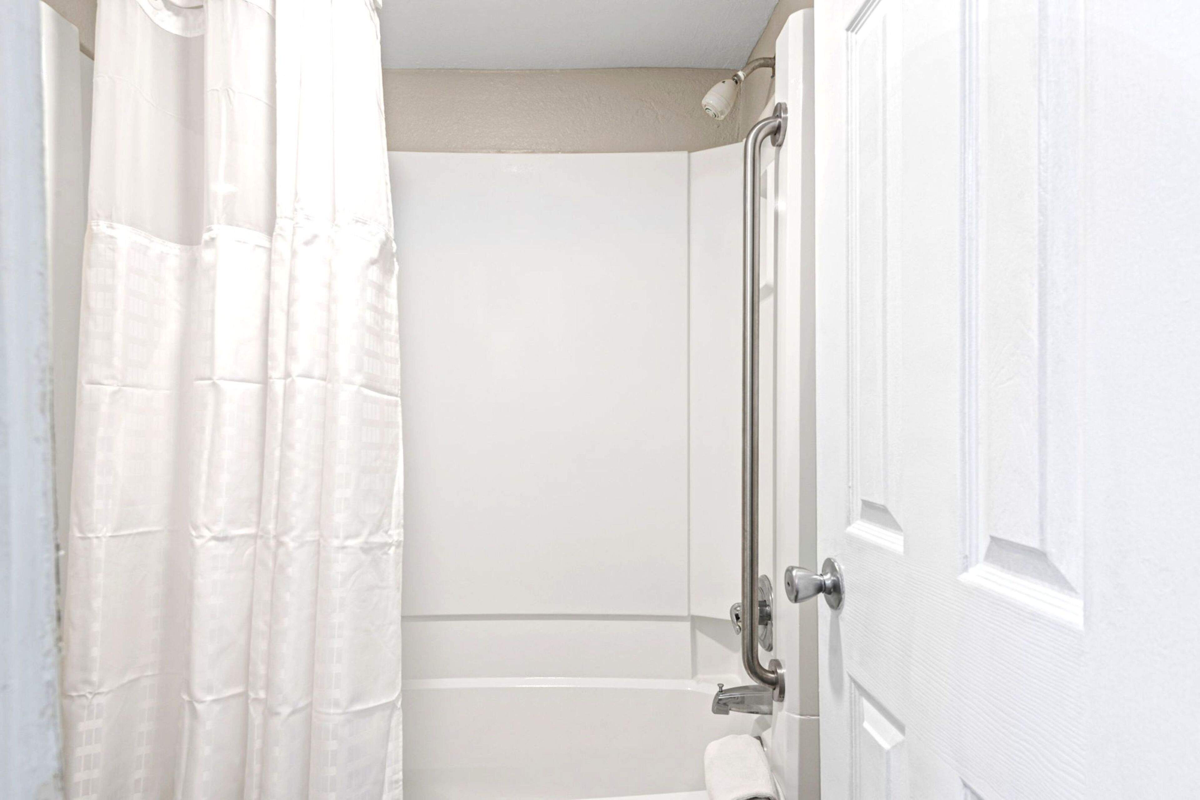 A bathroom with a shower, a toilet, and a door.