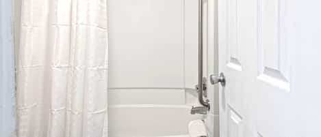A bathroom with a shower, a toilet, and a door.
