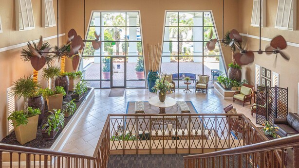 A spacious lobby with a central seating area, a staircase, and a view of the outdoor area through large windows. - Club Destin Condos (Destin)