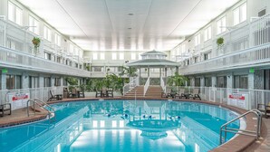 An indoor swimming pool with a central gazebo, surrounded by white railings and multiple windows. - Club Destin Condos (Destin)