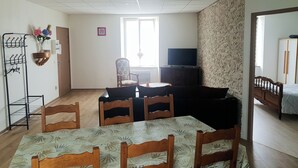 Una sala de estar con una mesa de comedor, sillas, televisor y sofá.