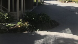 Un edificio moderno con balcón, un paseo cubierto y montañas al fondo.