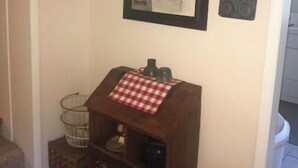 A wall with framed pictures, a small wooden shelf with a checkered cloth, and a metal basket. - The Strong Inn, Step back in time.  (Manhattan)