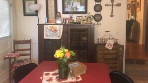 A dining area with a red tablecloth, a vase of flowers, and a wooden cabinet with kitchen items. - The Strong Inn, Step back in time.  (Manhattan)