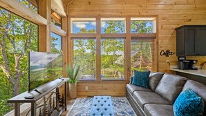 A cozy cabin interior with a large TV, wooden walls, a sofa, and a coffee station. - Adorable Cabin Near PF/Island Hottub GameRoom 2Bed Sleeps 5 Air Hockey Private (Pigeon Forge)
