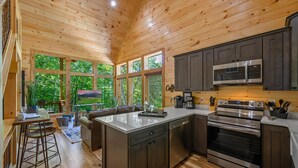 A modern kitchen with wooden ceiling, large windows, and a central island. - Adorable Cabin Near PF/Island Hottub GameRoom 2Bed Sleeps 5 Air Hockey Private (Pigeon Forge)