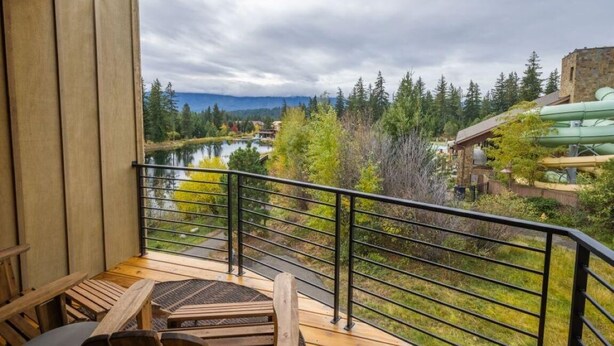 Ein Balkon mit Blick auf einen See, umgeben von Bäumen und einer Berglandschaft.