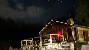 A cabin with a wooden exterior, a red-lit entrance, and a stone pathway leading to the door. - New Park Event Venue & Suites (Ithaca)