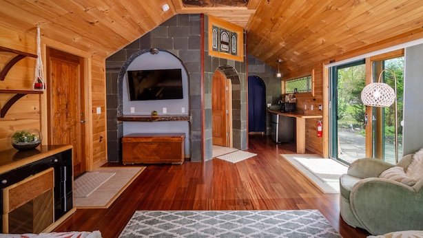 A wooden interior with a fireplace, a television, and a kitchen area. - New Park Event Venue & Suites (Ithaca)