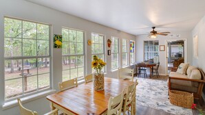 A dining area with a wooden table and chairs, a vase with flowers, and large windows offering a view of the outdoors. - Holly Lake Retreat w/ 2 Community Pools & Yard (Holly Lake Ranch)