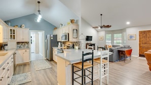 A spacious kitchen with a large island, white cabinetry, and a dining area with bar stools. - Holly Lake Retreat w/ 2 Community Pools & Yard (Holly Lake Ranch)