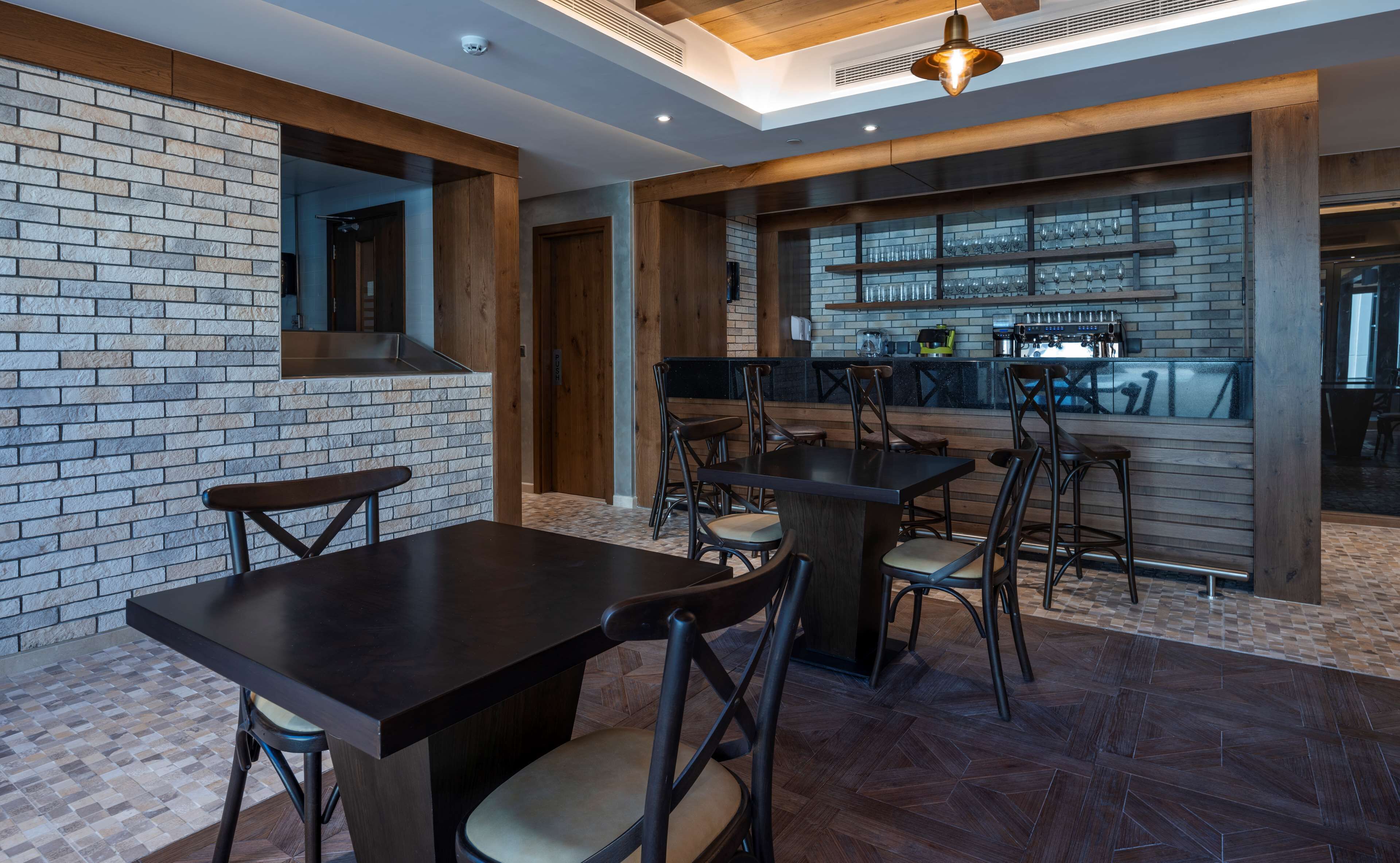 Un espace bar moderne avec un mur en briques, des poutres en bois et un comptoir avec des tabourets.