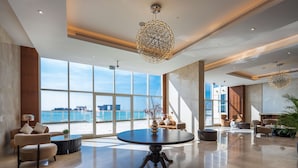 A spacious lobby with a round table, comfortable seating, and large windows offering a view of the sea. - Radisson Resort Ras Al Khaimah Marjan Island (Ras Al Khaimah)