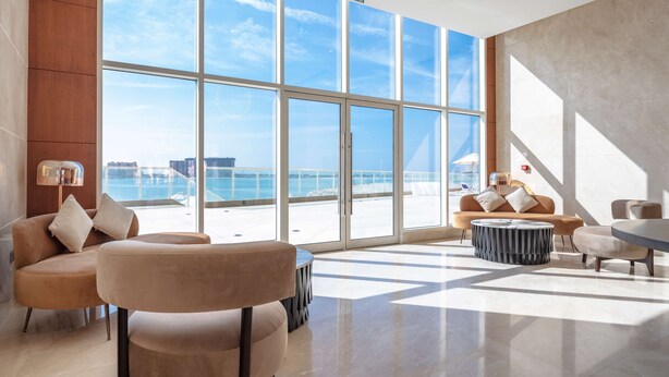 A spacious lobby with large windows, a modern sofa set, and a round coffee table. - Radisson Resort Ras Al Khaimah Marjan Island (Ras Al Khaimah)