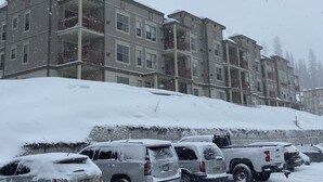A multi-story parking garage with snow-covered ground and parked vehicles. - Getaway to the Mountains (Vernon)