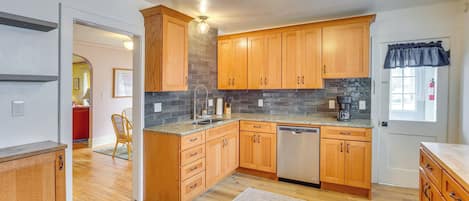 A kitchen with wooden cabinets, a dishwasher, and a granite countertop.