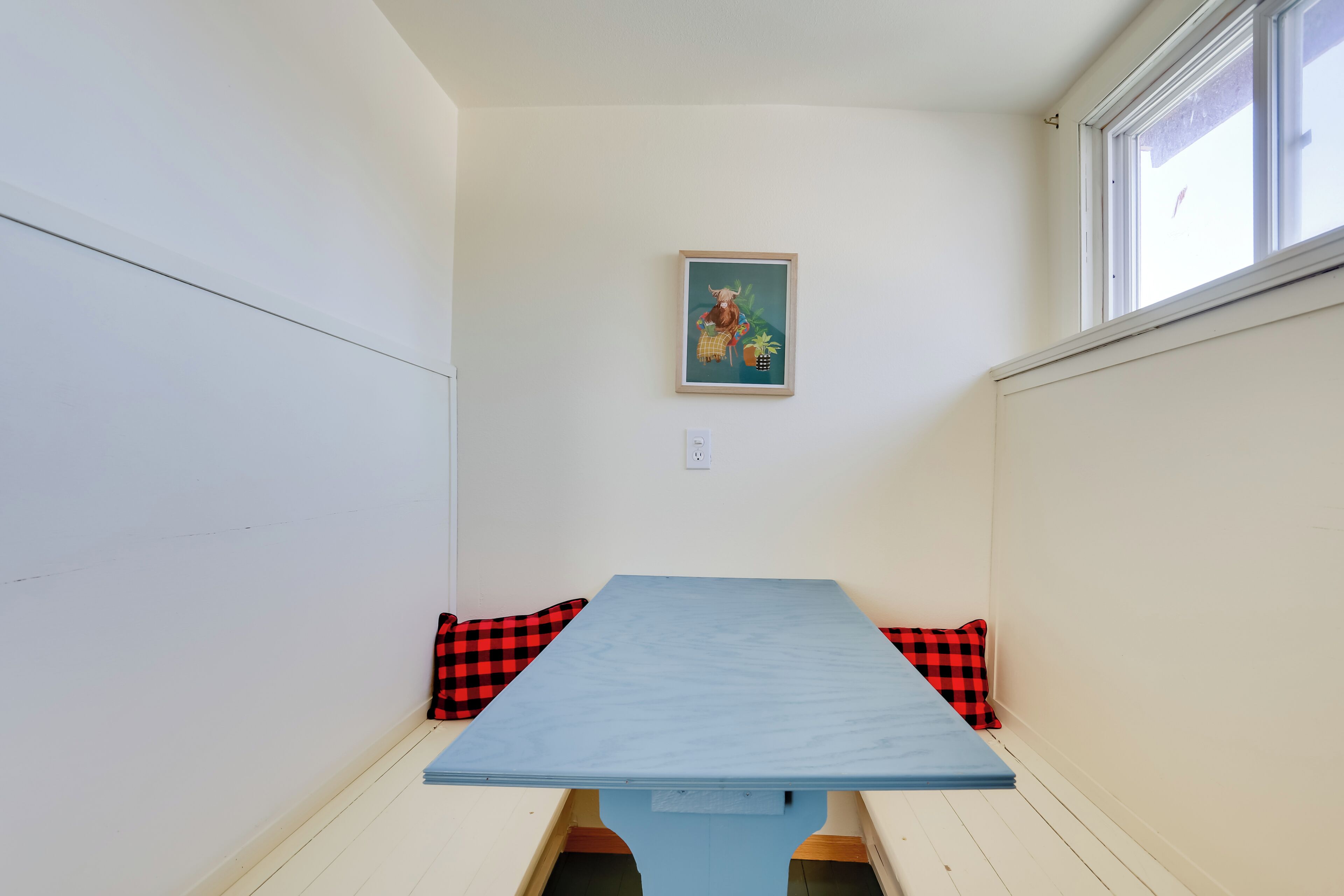 A small room with a blue table and red and black checkered cushions.
