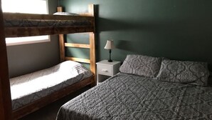 Ein Etagenbett mit einer unteren Schlafgelegenheit, ein Nachttisch mit Lampe und eine geblumte Bettdecke.
