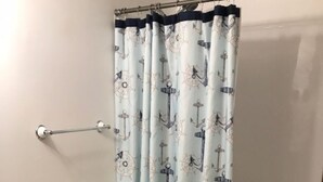 Ein Badezimmer mit Toilette, Waschbecken und einer Duschvorhang mit Meeresmotiven.