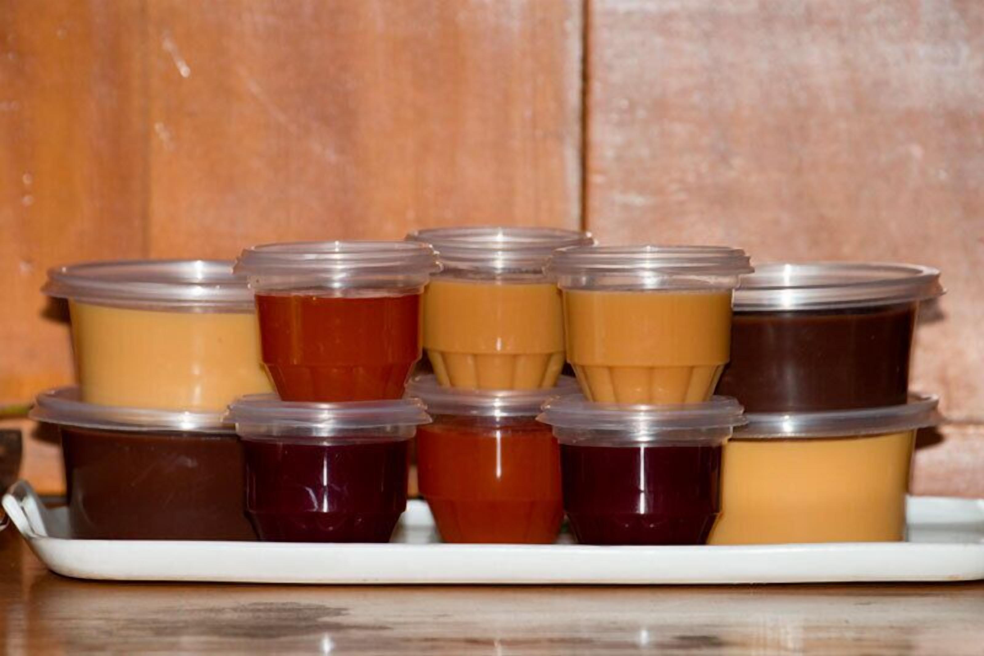 A tray of variously colored jellies or jams in plastic containers.