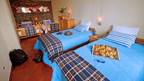 Een slaapkamer met twee bedden, een dressoir en een stenen muur.