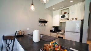 A modern kitchen with a dark countertop, white cabinets, a microwave, stove, and a refrigerator.