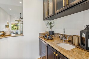A modern bathroom with a granite countertop, a sink, and a mirror. There is a potted plant on the countertop and a decorative bowl. - Bella Vida - 4000 PGA West Villa (La Quinta)