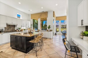 Una cocina amplia con una isla grande, muebles blancos y vistas a un paisaje montañoso.