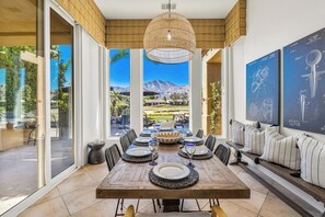 Comedor con una mesa de madera dispuesta para seis personas, ventanas amplias y vistas a la montaña.