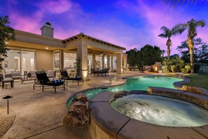 Una casa con piscina, mobiliario exterior y jacuzzi.