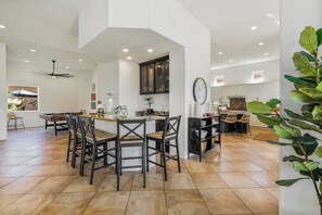 Una cocina amplia con una isla central, muebles oscuros y un comedor con sillas.