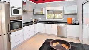 A modern kitchen with stainless steel appliances, white cabinets, and a black countertop. - El Olivo by Interhome (Moraira)