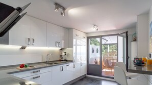 A modern kitchen with white cabinets, a built-in oven, and a dining area with a bar stool. - Vacation home Melon by Interhome (La Herradura)