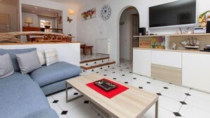 Een moderne woonkamer met een bank, salontafel en een aan de muur bevestigde televisie.