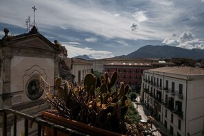 A courtyard with buildings, a cactus, and mountains in the background. - Domus Sicile - Panormus Cala a Mare (Palermo)