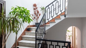 A staircase with a black railing, potted plants, and a view of a courtyard.