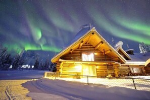 A log cabin with a pitched roof, a chimney, and a snow-covered landscape. - Come stay in this massive historic log mansion (Fairbanks)