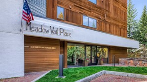 Un edificio moderno con un letrero que dice "Meadow Vail Place" y una bandera.