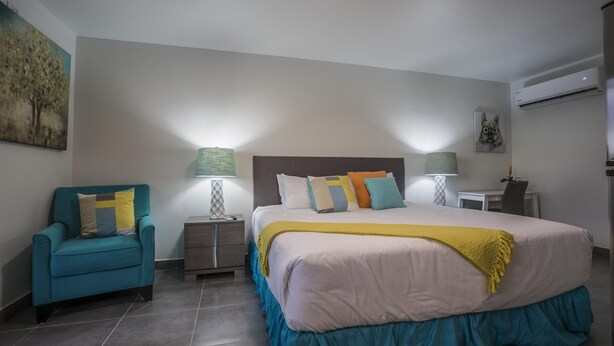 Une chambre d’hôtel avec un lit, une chaise, une table de chevet et une lampe.