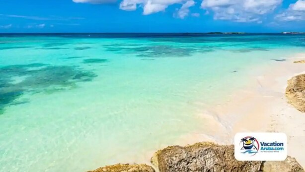Una playa con aguas turquesas cristalinas y arena blanca, con el logo de VacationAruba.com en la esquina inferior derecha.