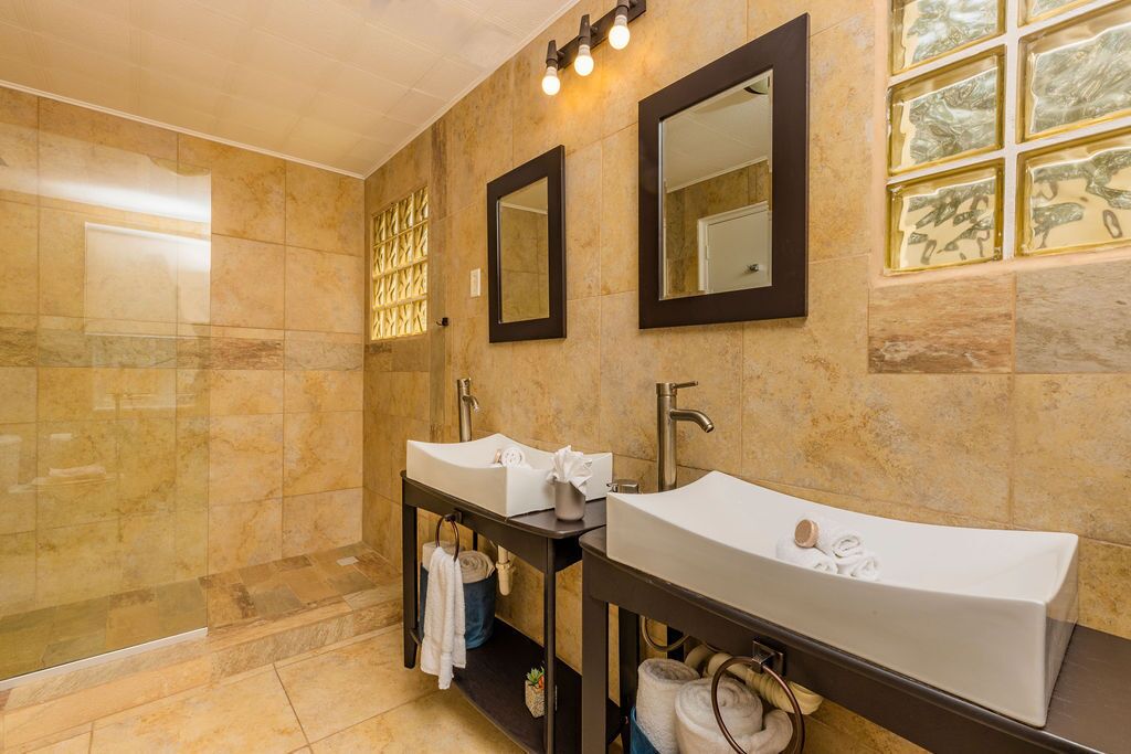 Un baño con dos lavamanos, un espejo y una ducha.