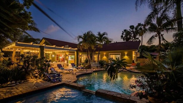 A pool area with lounge chairs and a building with a red roof. - Spacious 5BR Home w/ Amazing Garden & PrivatePool (Noord)