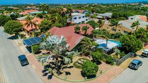 A residential area with houses, palm trees, and a swimming pool. - Spacious 5BR Home w/ Amazing Garden & PrivatePool (Noord)
