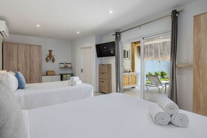 Een hotelkamer met twee bedden, een televisie, een schuifglasdeur naar een balkon en een houten garderobe.