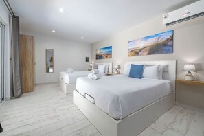 Une chambre d’hôtel avec deux lits, une grande fenêtre, une armoire en bois et un climatiseur fixé au mur.
