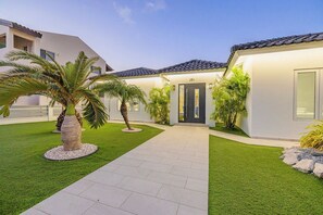 Une maison moderne avec une pelouse bien entretenue, un chemin piétonnier dallé et une porte portant l’inscription « 15A ».